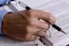 photo of a hand holding a pen over a piece of paper filled with typing