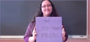 A woman holding a sign that says "The Loud Hands Project"