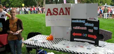 Ohio State campus activity fair; person next to a table with signs about ASAN