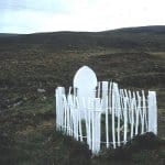 photo of a white gravestone inside a white fence