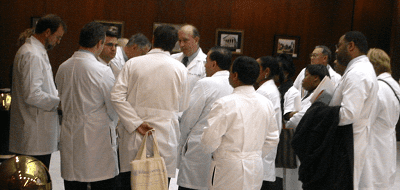 Several people wearing white doctor's coats faced away from the camera