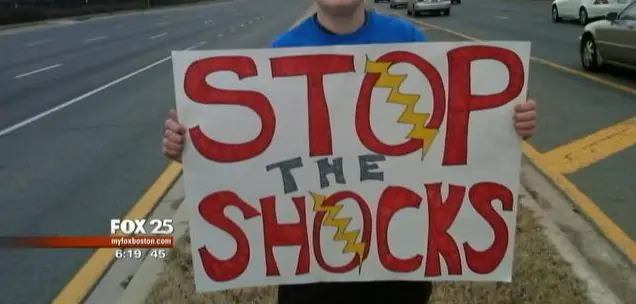 a person holding a sign that says Stop the Shocks