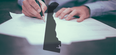 A person signing legislation with a silhouette of Delaware overlaid