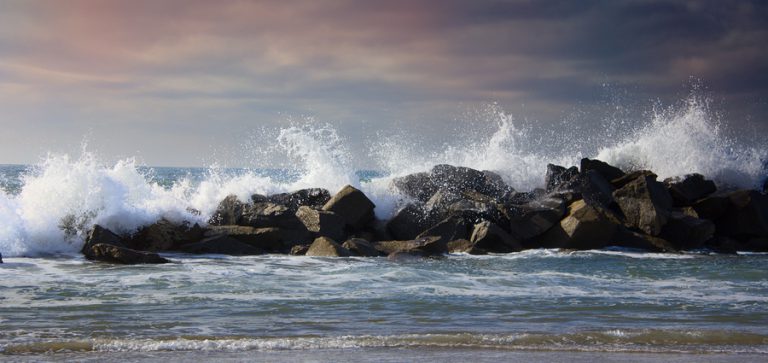 stormy ocean waves splashing high against rocks