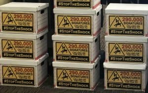 Photo of ten boxes of signatures with labels reading "290,000 signatures calling on the FDA to #StoptheShock"