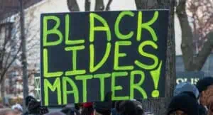 photo of a black sign with green lettering reading "black lives matter!"