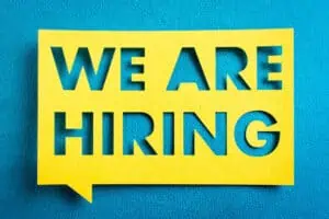 A yellow paper against a blue background says We Are Hiring